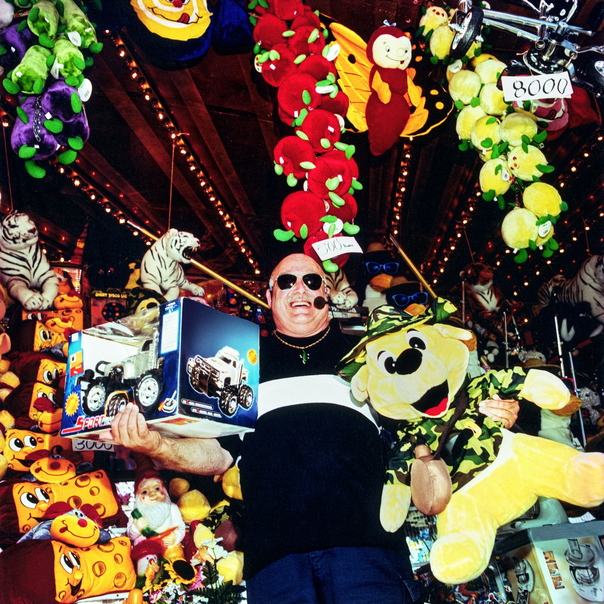 Large_MS PPT_Web-Bald man holding a remote-controlled car and big yellow stuffed animal at a fair.jpg