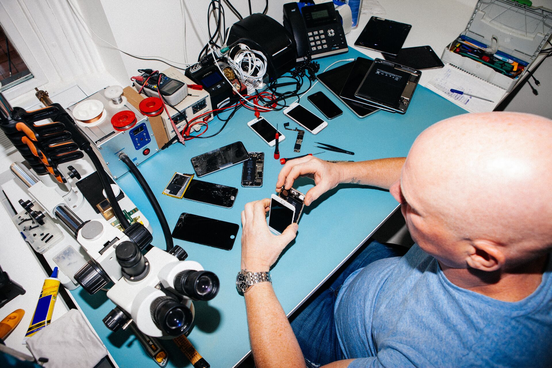 Large_MS PPT_Web-A bald male technician repairing mobile phones behind his desk at work.jpg