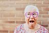 Large_MS PPT_Web-A senior woman with heart-shaped glasses makes a funny face outside in front of a brick wall.jpg