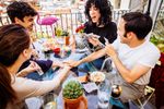 Large_MS PPT_Web-Four friends laugh and play a card game on the balcony while touching hands on the table.jpg