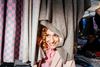 Large_Web and Screen-A woman smiles as she peeks out from behind woven scarves at a market stand.jpg