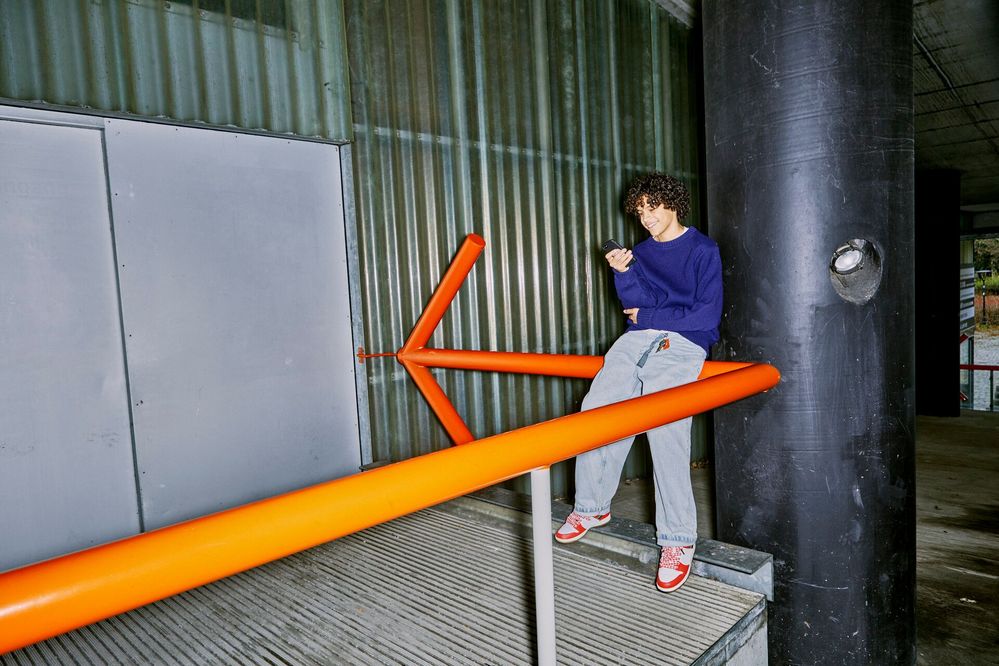 Large_Web and Screen-A teenage boy leans on a railing and checks his phone.jpg