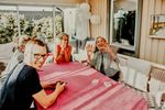 Large_Web and Screen-A happy senior woman sits at a table with playing cards, surrounded by her family members outside on the patio.jpg
